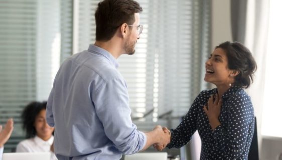 boss congratulating employee while colleagues applaud